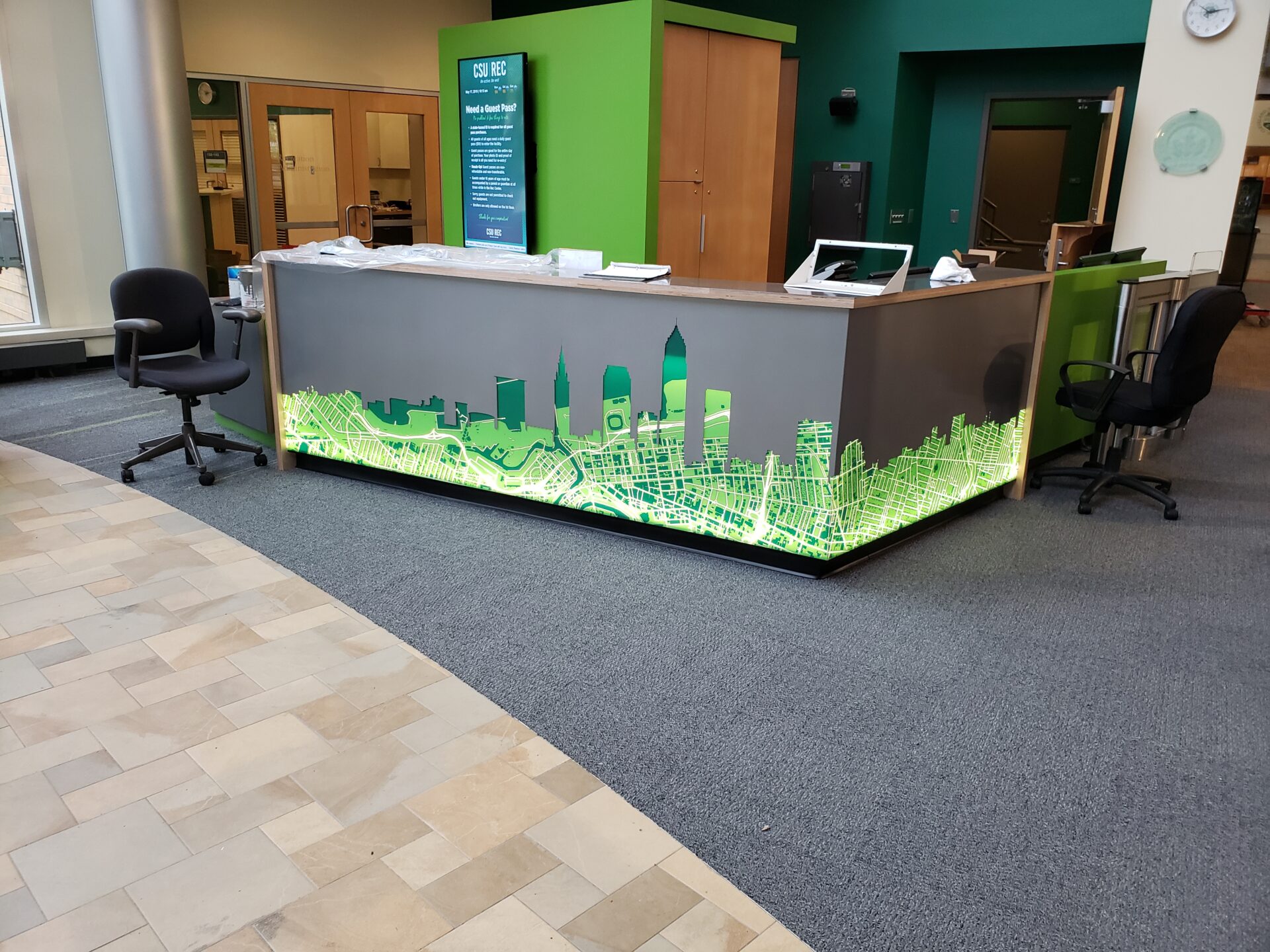 A green reception desk with a city skyline on it.