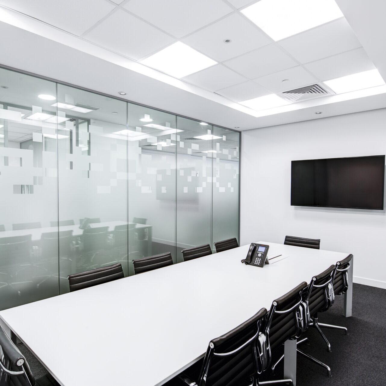 A conference room with glass walls and a white table.